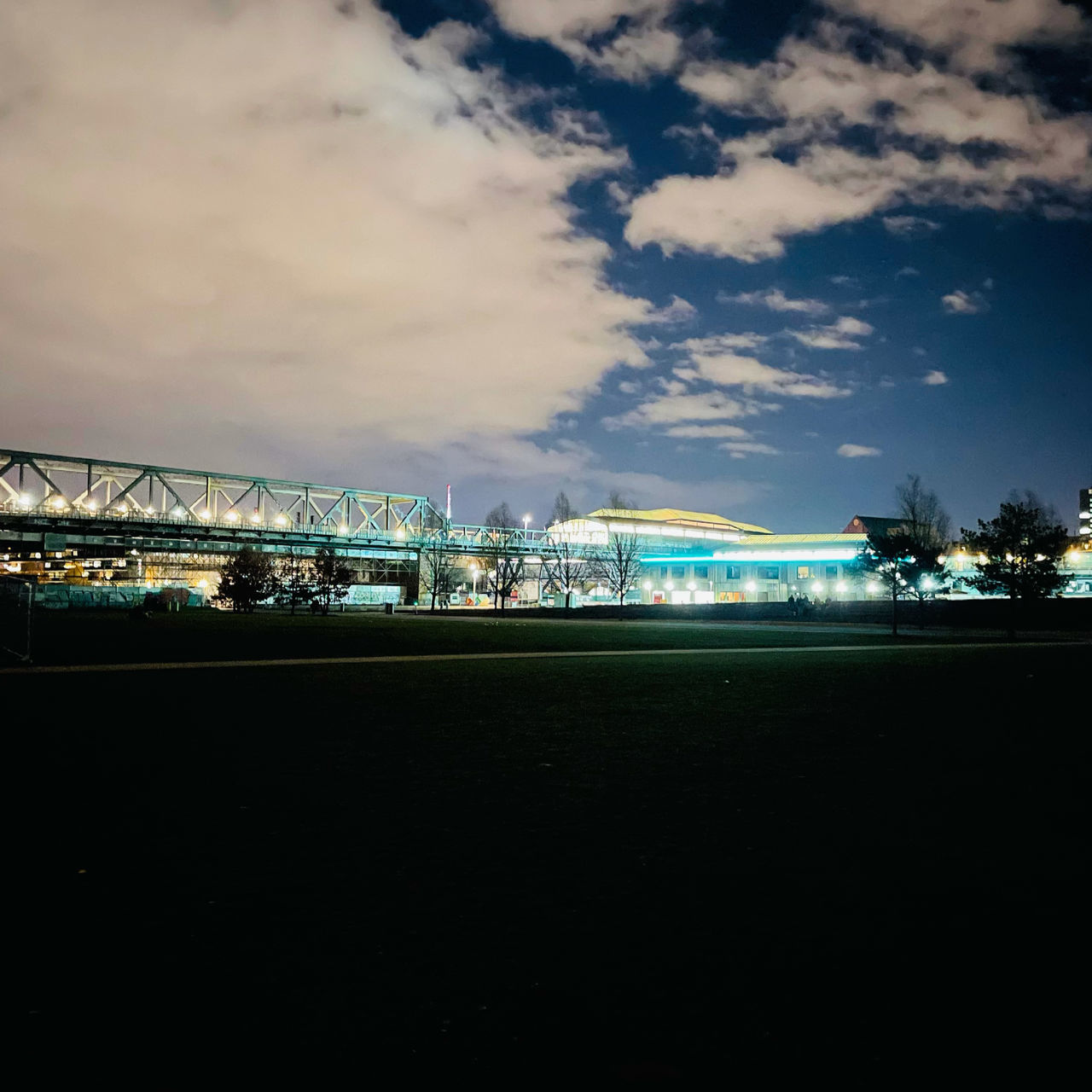 ILLUMINATED BRIDGE OVER CITY AGAINST SKY AT NIGHT