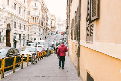 Rear view of woman walking along buildings