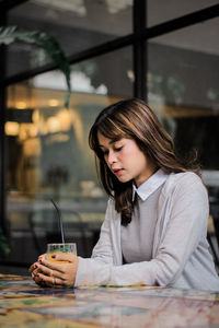 Young woman drinking glass on table at restaurant