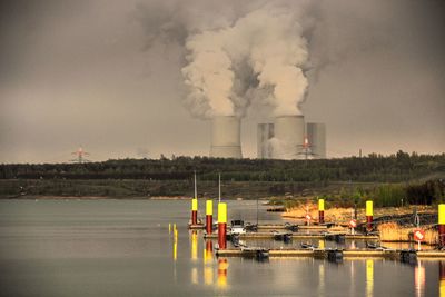 Smoke emitting from factory against sky