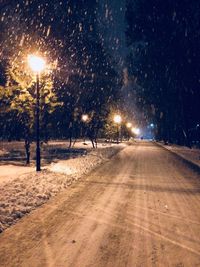 Street lights on snow covered road at night