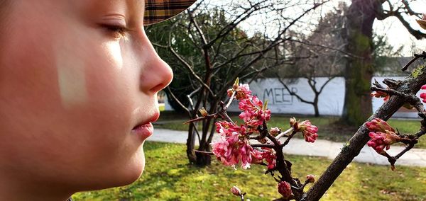 Close-up portrait of young woman by flower tree