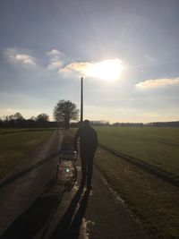 Rear view of man walking on road against sky