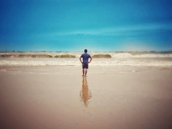 Rear view of man on beach against sky