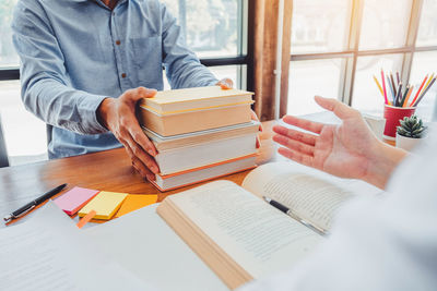 Midsection of man reading book on table