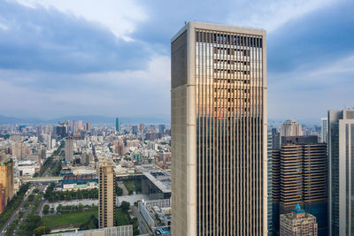 Modern buildings in city against cloudy sky