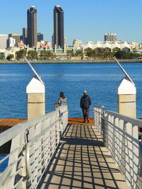 Rear view of people standing by sea against sky