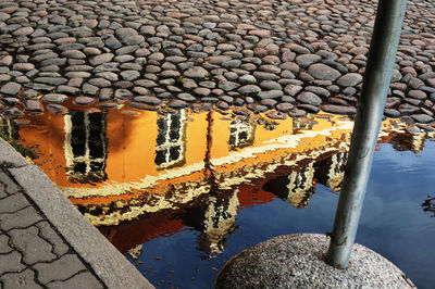 Reflection of building in puddle on cobbled street