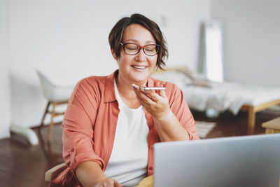 Portrait of smiling young woman using mobile phone at home