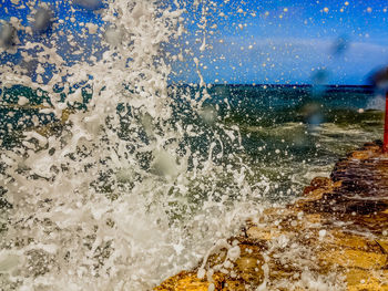 Close-up of water splashing in sea against sky