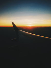 Close-up of airplane wing against sky during sunset