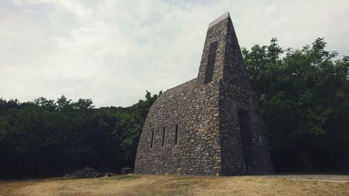 Old temple on field against sky