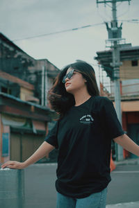 Young woman looking away while standing against built structure