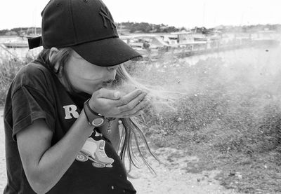 Rear view of man drinking water on land