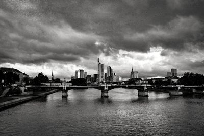 Bridge over river in city against sky