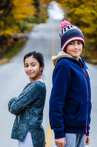 Portrait of smiling siblings standing on road during autumn