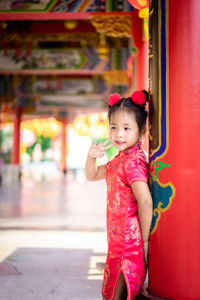 Side view of cute girl wearing traditional clothing standing by column