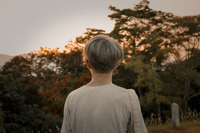 Rear view of young man standing against trees and plants
