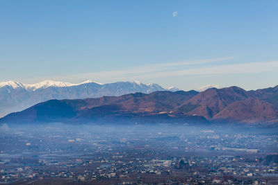 Aerial view of snowcapped mountains against blue sky