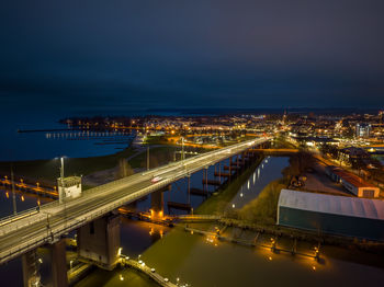 Illuminated bridge over river against sky at night