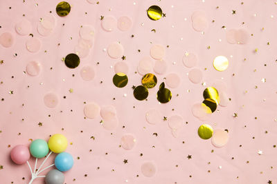 Glitter background with colorful balls. golden stars in the form of confetti on pink background.