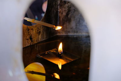 Close-up of hand holding lit candles in temple