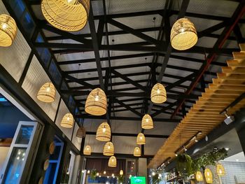 Low angle view of illuminated pendant lights hanging from ceiling in building