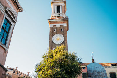 Low angle view of clock tower amidst buildings against sky