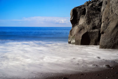 Rock formation on beach against sky