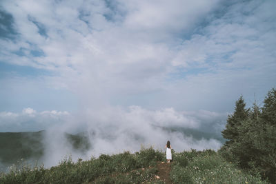 Rear view of woman standing on field against sky