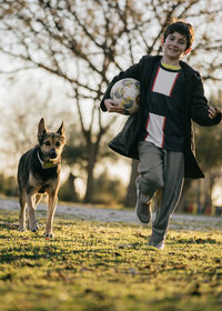 Kid with ball running from dog playing catch-up game