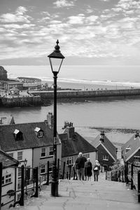 Street light by sea against sky in city