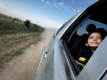 Close-up of boy in car against sky