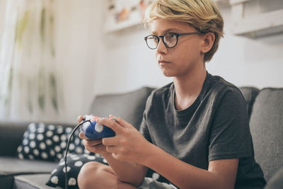 Midsection of woman holding eyeglasses while sitting at home