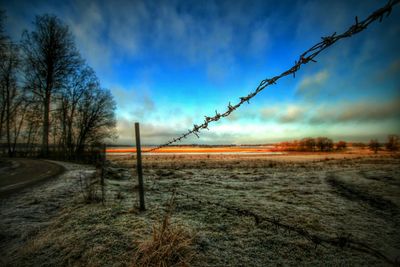 Fence on field against sky during winter