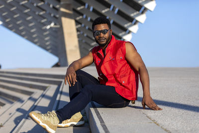 Portrait of man wearing sunglasses sitting on steps against built structure