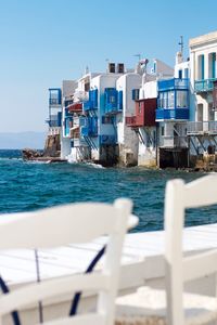 Buildings by sea against clear blue sky