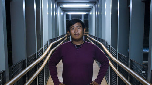 Portrait of men standing against railing on corridor pedestrian bridge