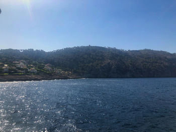 Scenic view of lake by mountains against clear sky