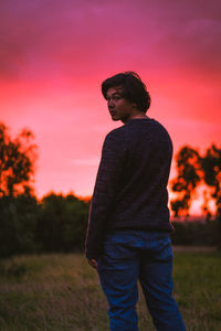 Man standing on field against sky during sunset