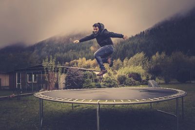 Man jumping over trampoline against sky