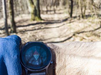 Close-up of hand holding camera against trees