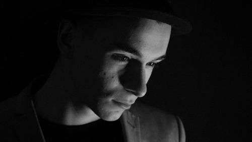 Thoughtful man looking down against black background