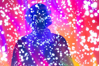 Defocused image of silhouette woman with illuminated lights