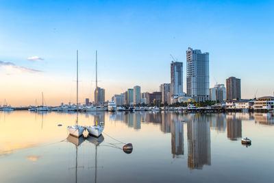 Sailboats in city by buildings against sky