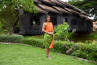 Full length portrait of smiling woman standing on grass