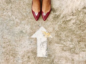 Low section of woman standing by arrow symbol on street