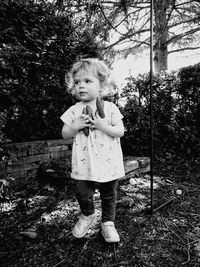 Girl holding pine cones while standing in yard