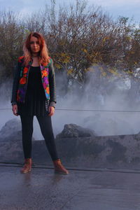 Portrait of woman standing against tree