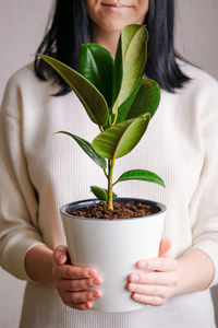 Midsection of woman holding plant